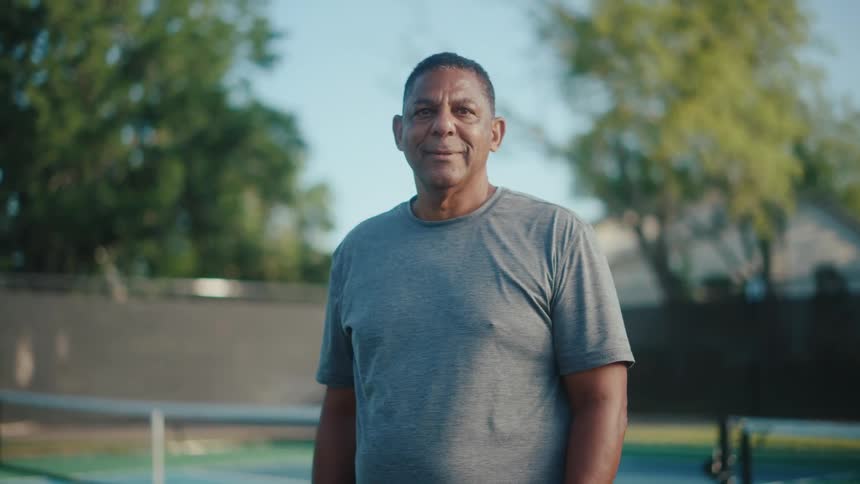An ethnic man smiling next to tennis court