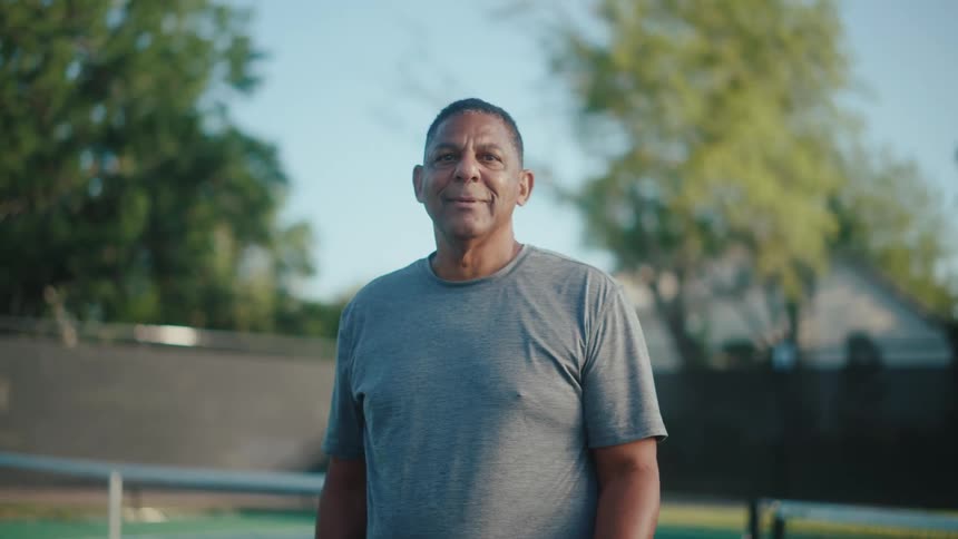 Man on a tennis court smiling