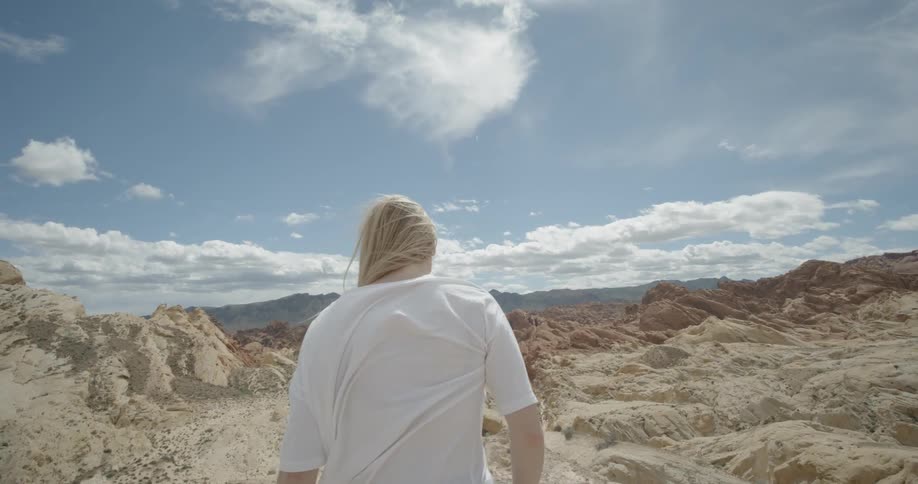 A woman in a white t-shirt walks to the rock edge