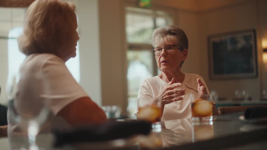 Two elderly women talking and having drinks at a bar