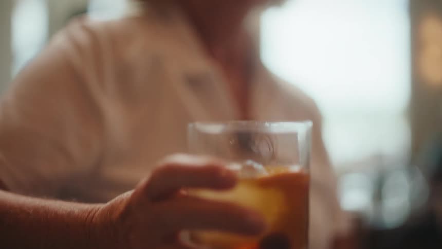 An elderly woman having a drink from a whiskey glass