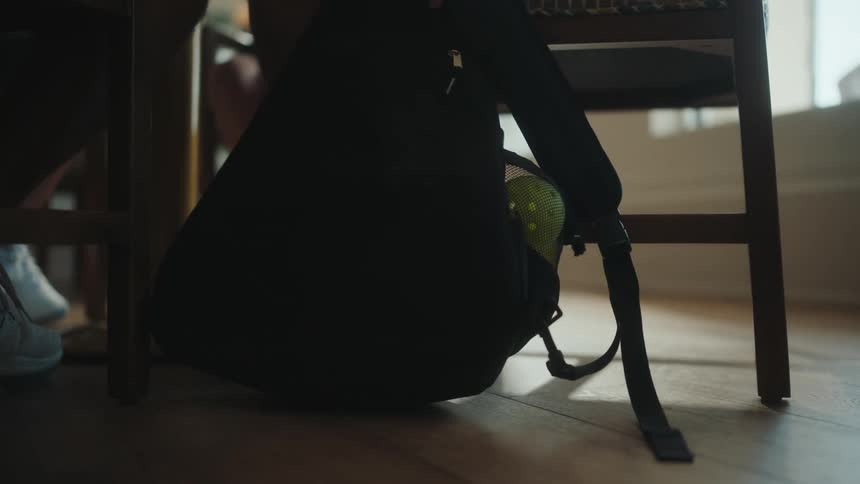 A man sets his backpack with sports equipment down as he is seated for lunch