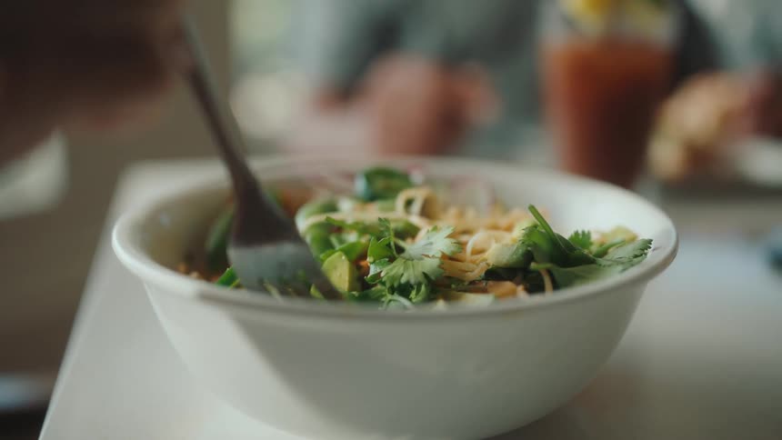 A person uses a fork to take a bite of a healthy salad
