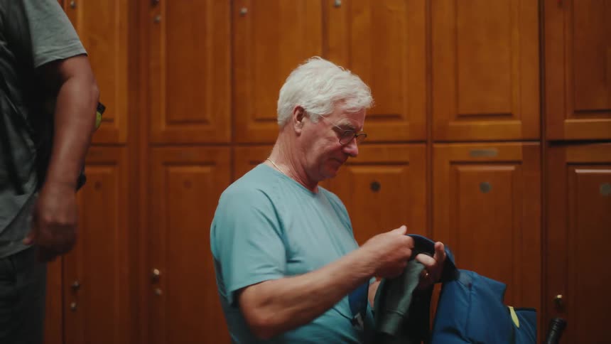 Two men pack up their things in a locker room