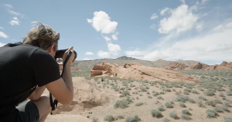 A man is taking photographs of a valley below