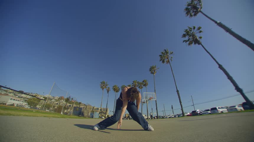 Woman dancing in a park on a blue sky day with palm trees around