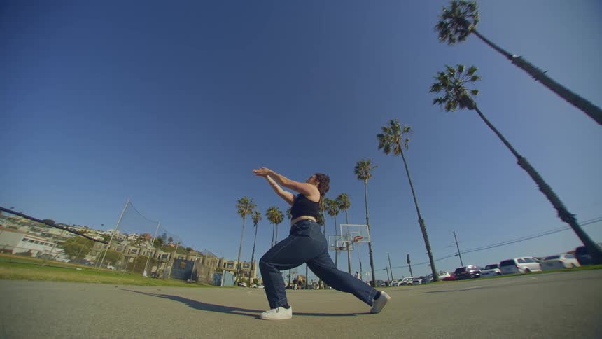 Woman in a park dancing moving her legs and arms