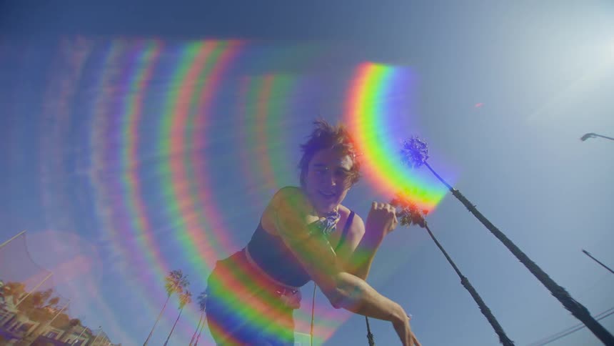 A young woman doing dance moves with her arms outdoors on a day with a clear blue sky