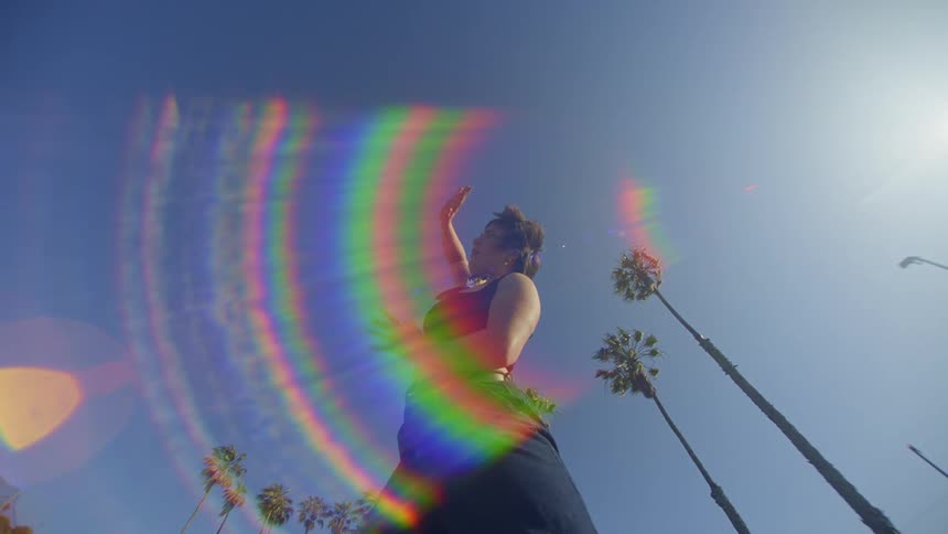 A denim clad female dancer throwing out moves outdoors near palm trees