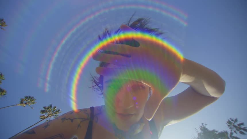 A woman making gestures with her hand and there is a flare of colored lights in front of her