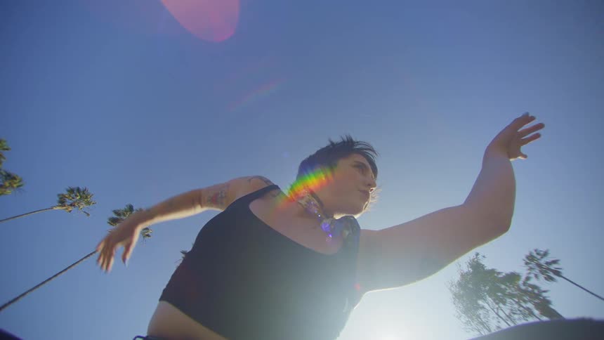 Woman in jeans dancing outdoors with blue sky