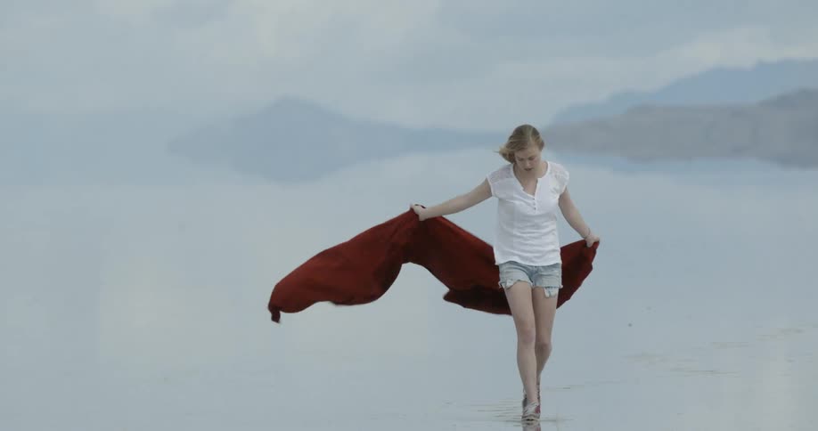 A woman holds a red sheet behind her on a windy day