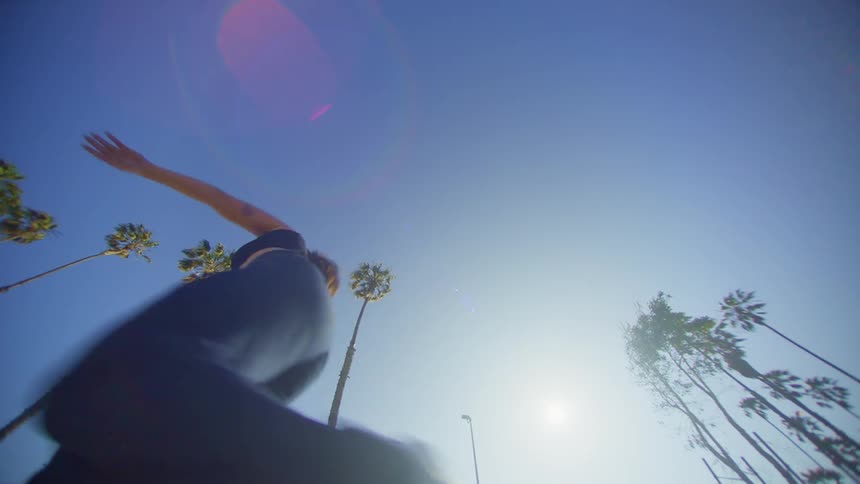 A woman dancing against a clear blue sky surrounded by tall slender palm trees