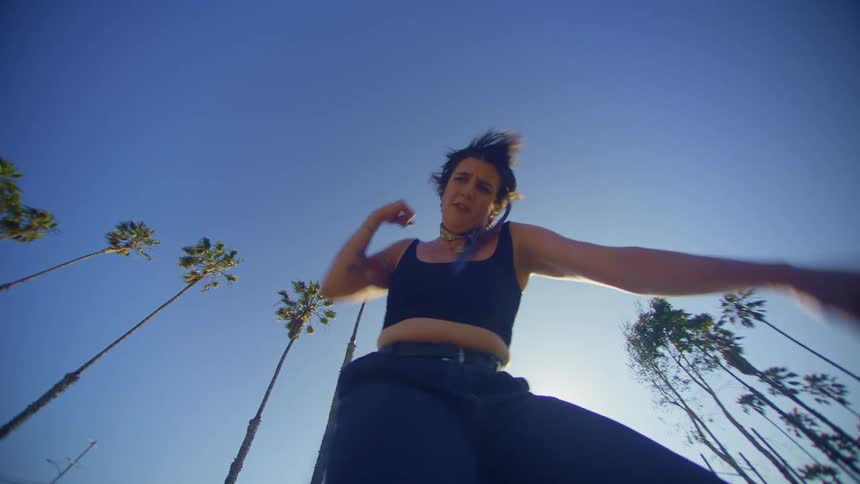 A woman is dancing against a clear blue sky