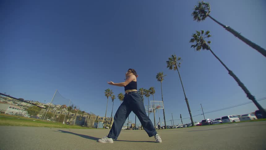 Woman in jeans and a black top in an openair environment dancing