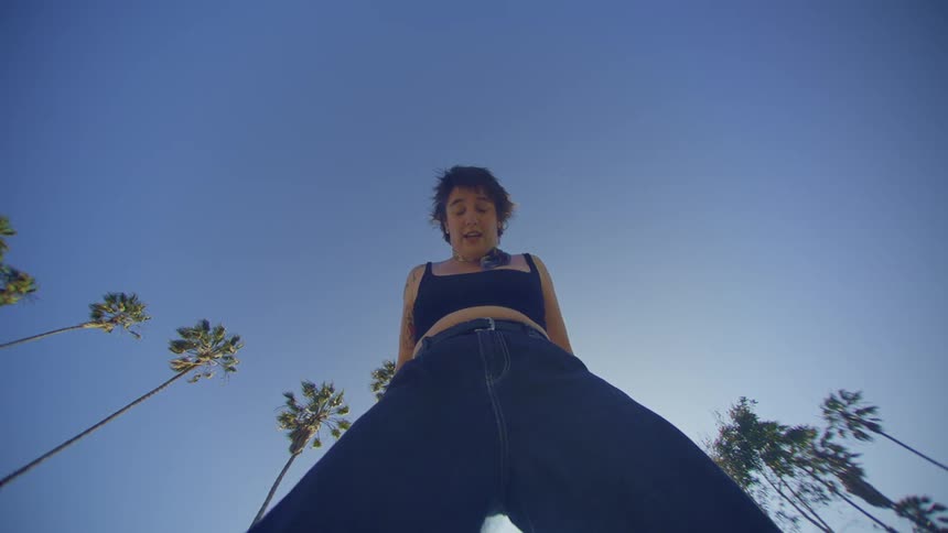 Woman in jeans dancing and an outdoor environment with the blue sky