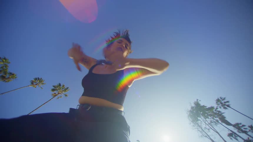 Upward view of a woman dancing against a blue sky