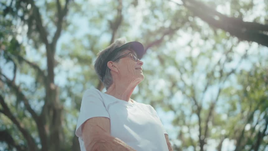 Elderly woman in an open space with trees talking and smiling