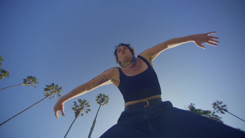 A tattooed woman dances outdoors