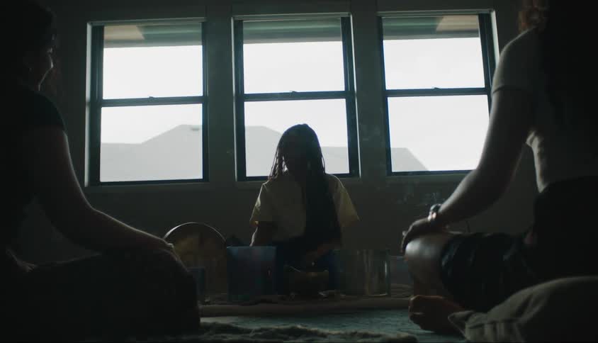Three people sitting in a room with a woman reading letters