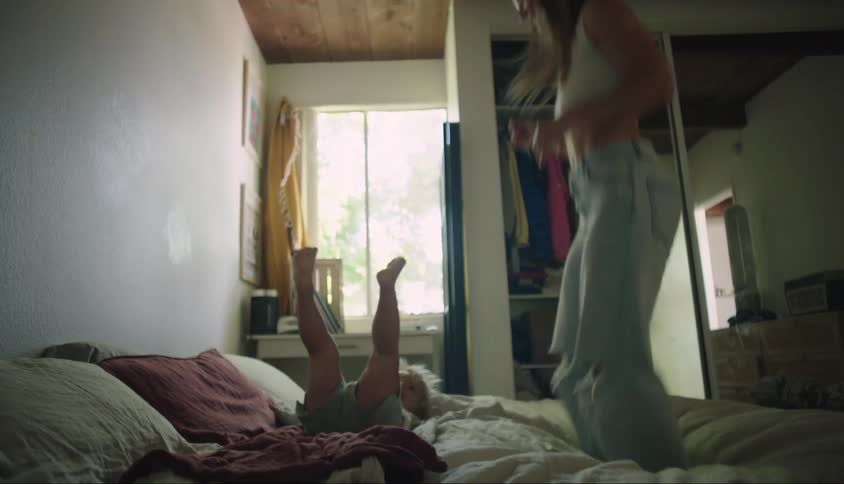 Mother and daughter playing jumping on the bed