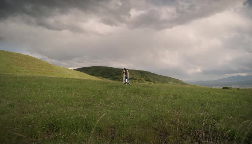 Couple holding hands in a natural environment with green hills