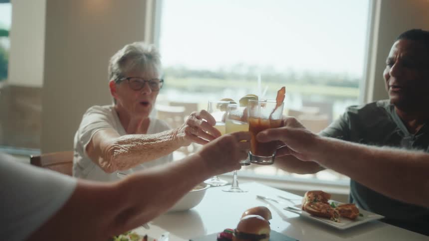Four people sitting at a table toasting with drinks