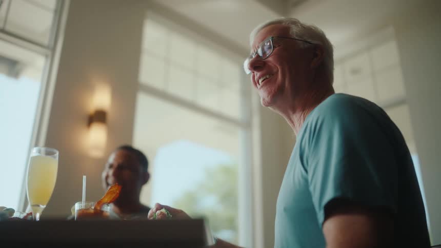 Two men laugh with drinks at a restaurant