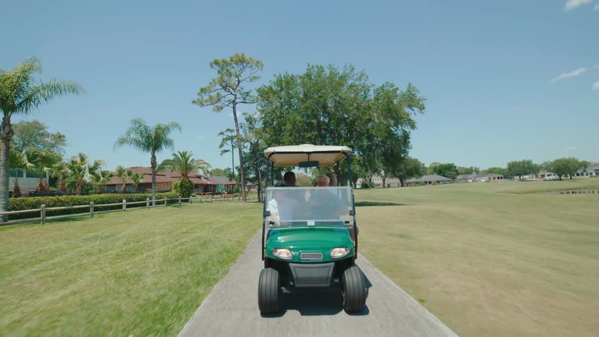 Elderly people on a golf court riding through the golf course
