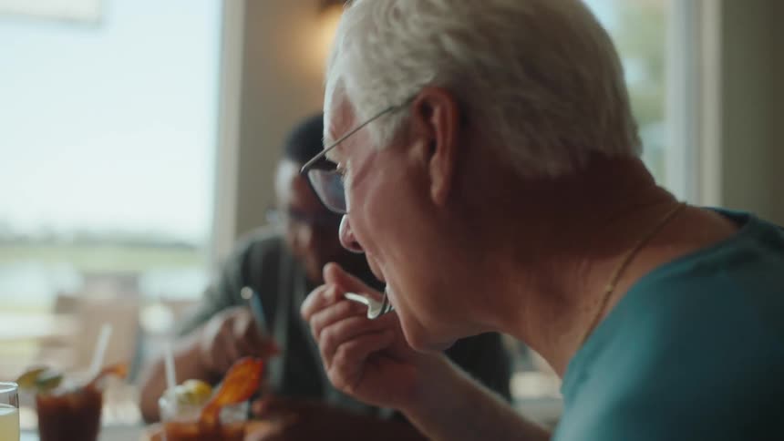 An old man takes a bite from a full plate of food