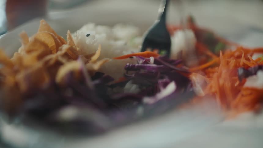 A person collects food with a fork from a plate