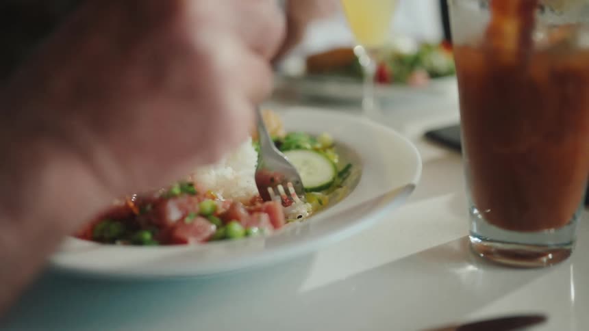 Closeup of a plate with food and a persons hands eating it