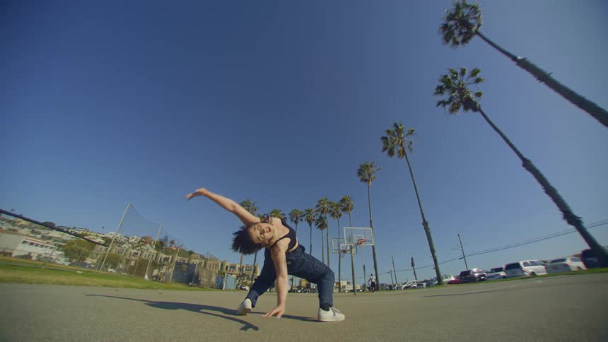 A woman dances on an outdoor basketball court