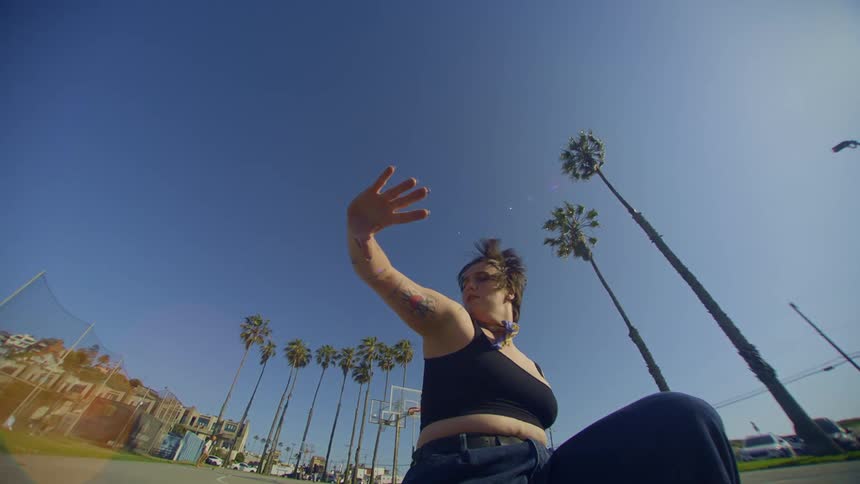 A woman dances outdoors near a suburb and parking lot