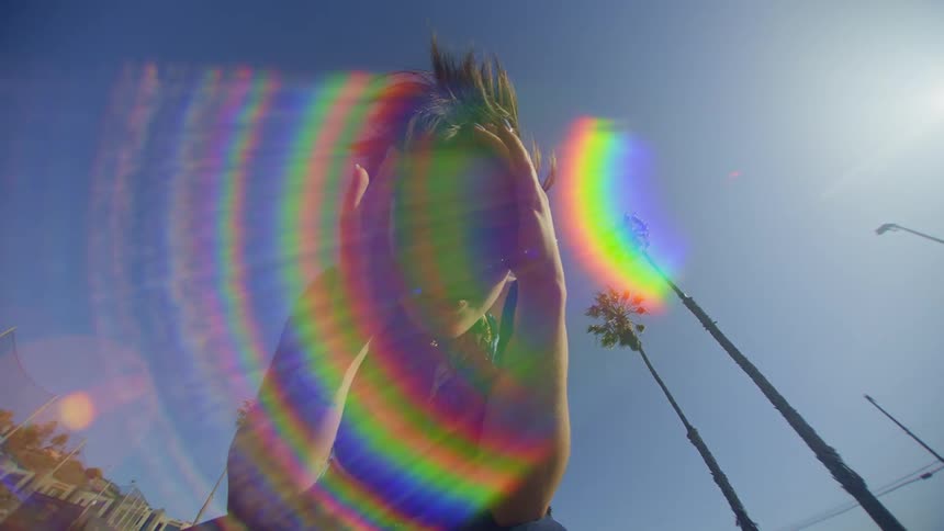 A woman is putting her two hands forward and there is a flare of colored light in front of her