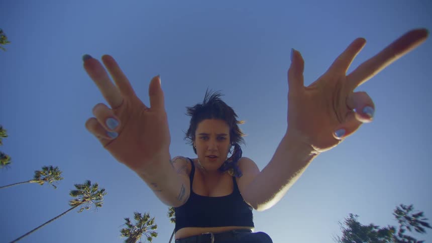 Portrait of a woman opening her palms while standing outdoors on a blue sky day