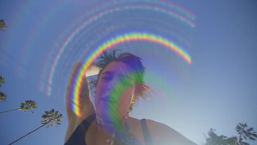 A woman waves her arms around dancing under the bright sun