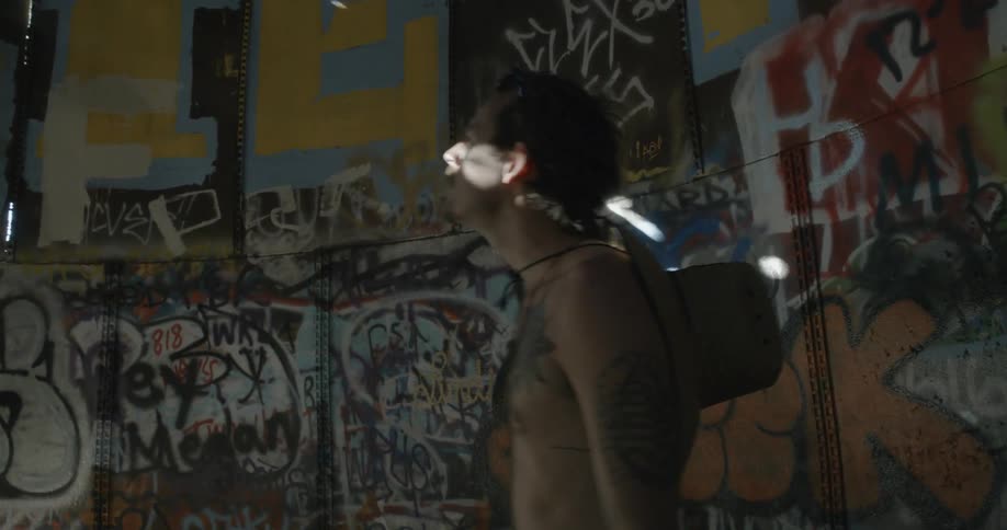 Shirtless man standing in a graffiti covered room