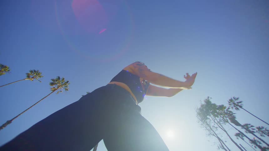 A dancer busts out the moves near numerous palm trees