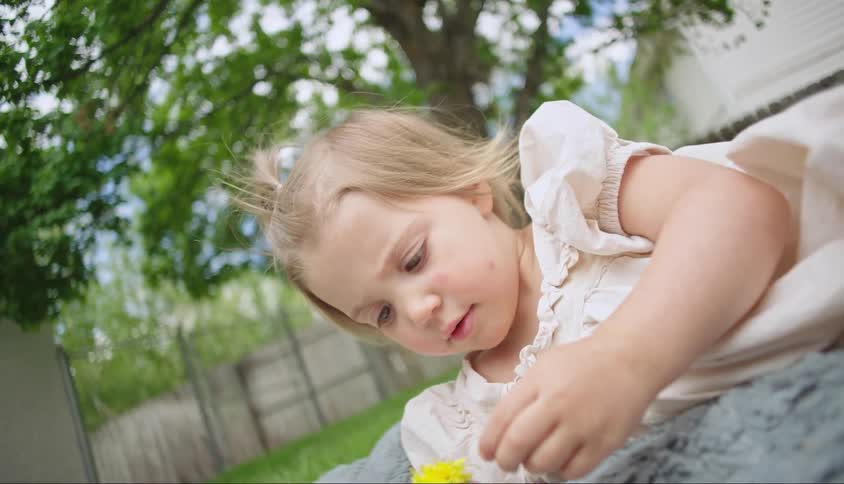 A child plays with a flower in the yard
