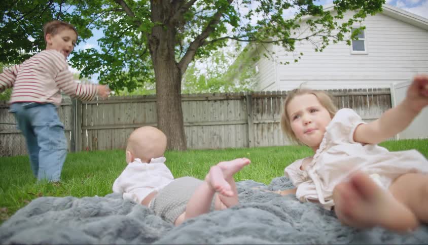 Three children playing in a garden in the backyard of a house