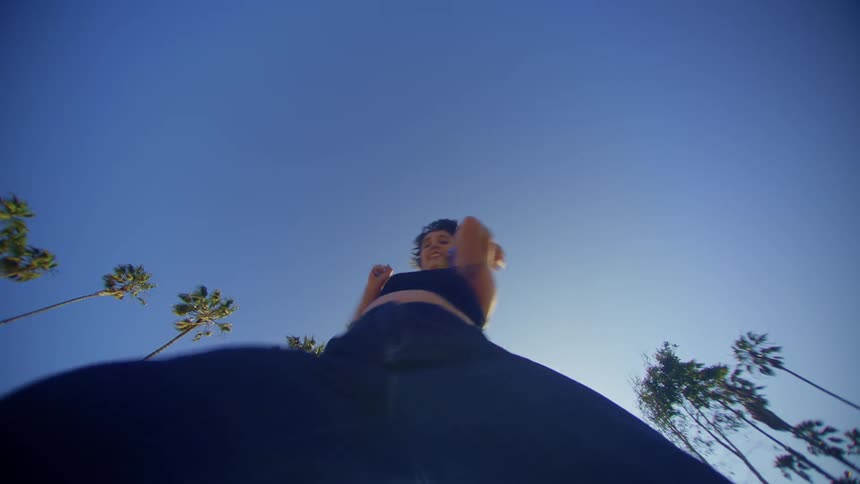 A woman is dancing under a clear sky