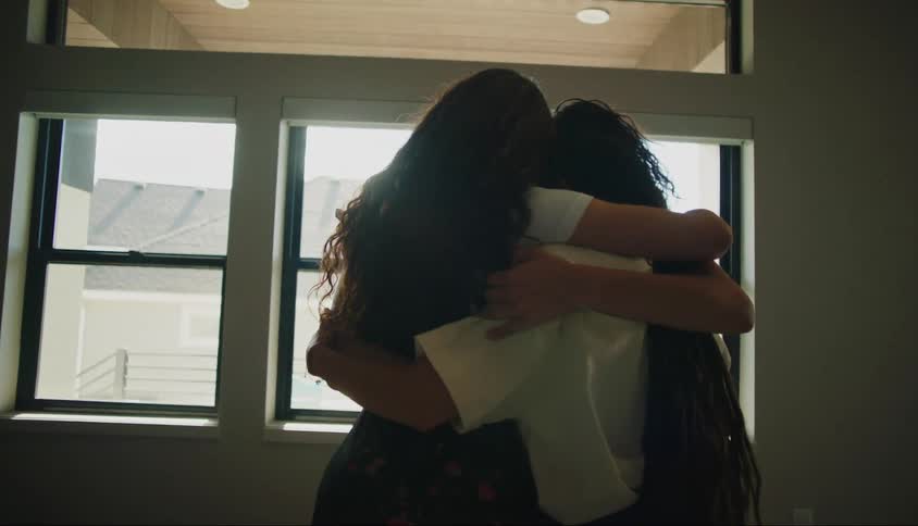 Young female friends share a group hug near a window