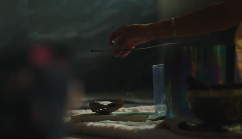 A closeup of a hand holding an incense stylus over a small ink container