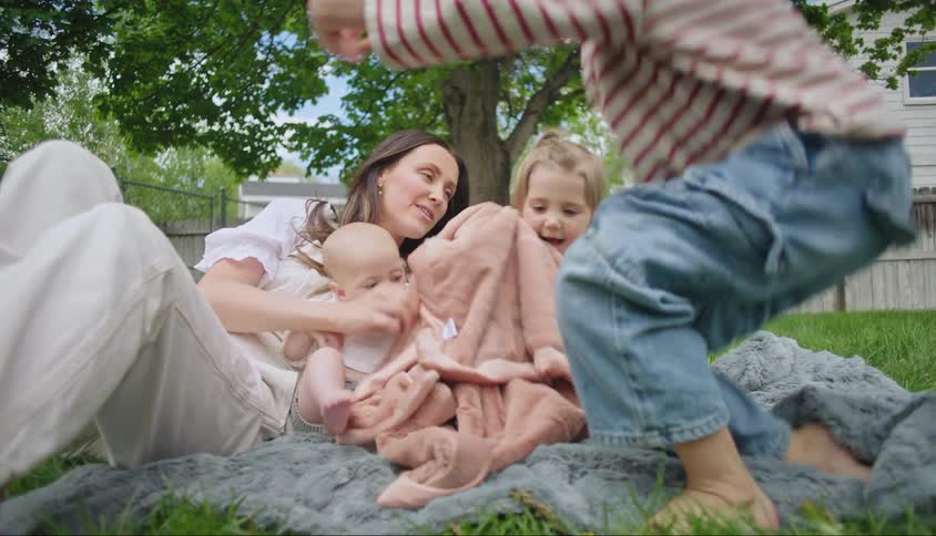 A mother and three children outside sitting in the yard and playing