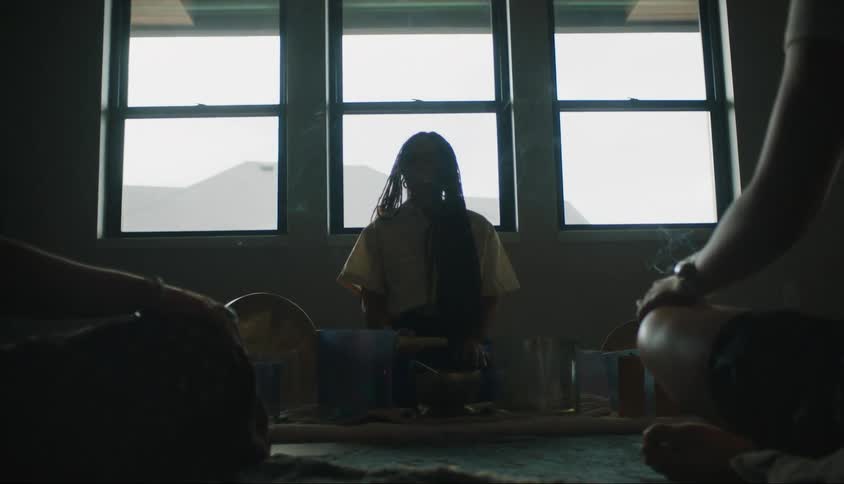 Three people sitting indoors near windows and doing meditation