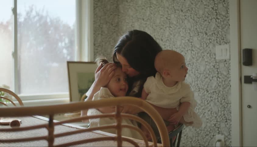 Mother with a baby on her lap and hugging her other little daughter