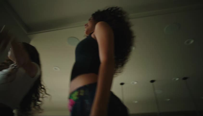 Four teenage girls dance together inside a house