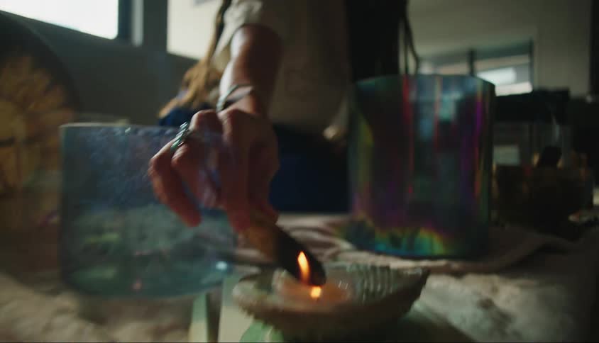 Smoke rises as woman holds cylindrical item in candle flame