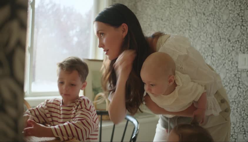 Mother holding a baby fixing her hair and three other children around her